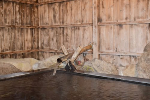 Le bain commun du Minshuku Yamanosato, palissades de bois et bassin entouré de pierres