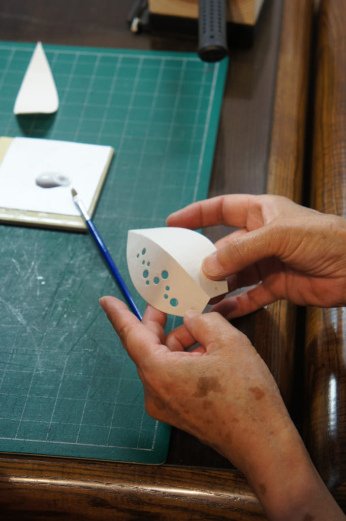 Gros plan sur les mains de l'artisane montant comment assembler les parties de la lampe