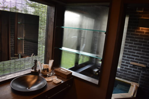 L'espace salle de bain, aux matières nobles et sombres, éclairé par grandes fenêtres