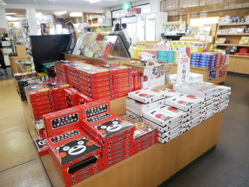 Intérieur de la boutique de souvenirs, où l'on peut voir des boîtes de gâteaux à l'effigie de Kumamon