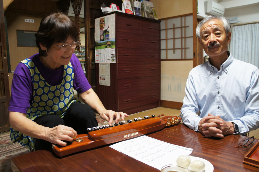 Le couple Yonemura dans leur salon, Keiko joue du taishogoto