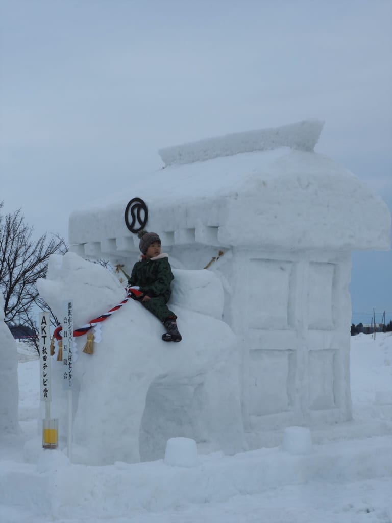 Enfant sur une sculpture de chien Akita au festival Inukko Matsuri
