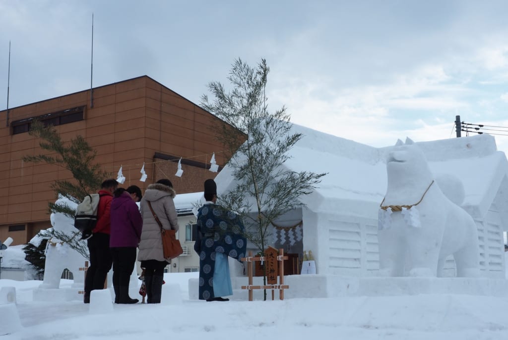 Japonais se recueillant devant un temple sculpté dans la neige pour le festival Inukko Matsuri