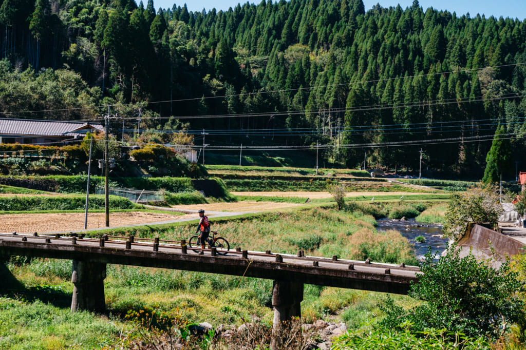 Guide à vélo traversant un petit pont dans la campagne à Kumamoto
