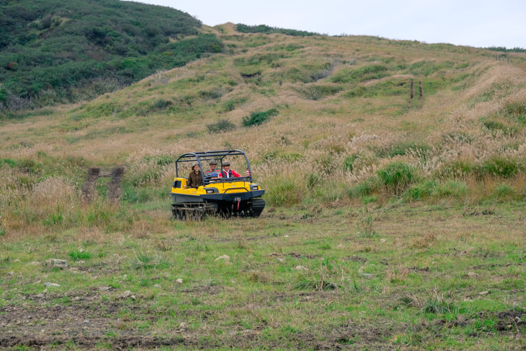 Véhicule tout terrain jaune, dans le paysage du mont Aso