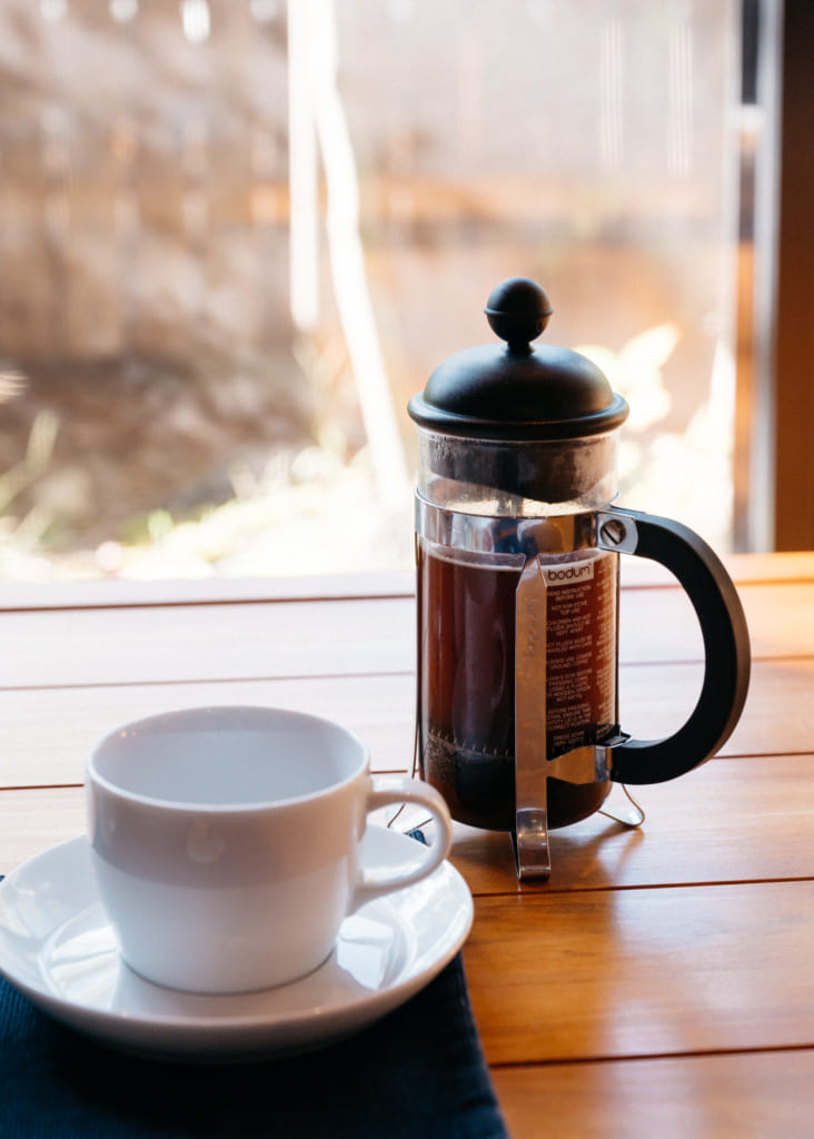 Cafetière à piston et tasse sur la table baignée de soleil