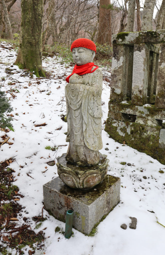 statuette japonaise vêtue d'un bonnet et d'une écharpe rouges