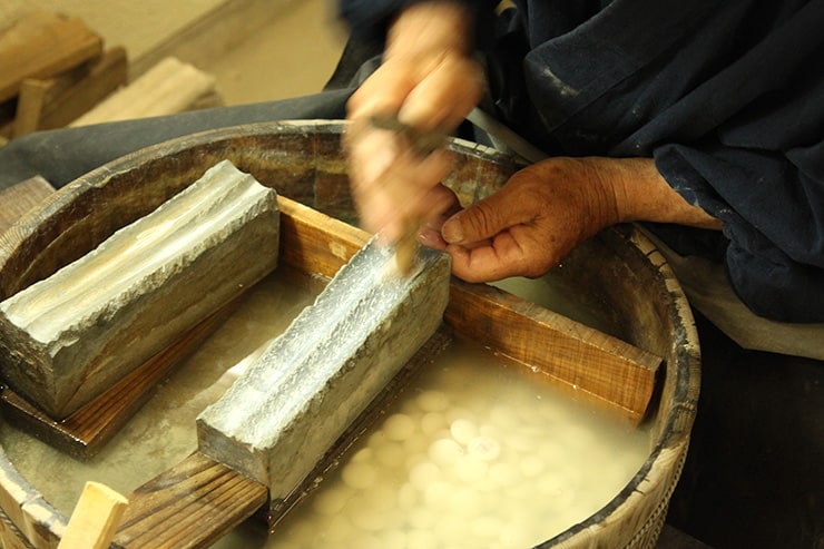 artisan entrain de polir des pierres de go en coquillage