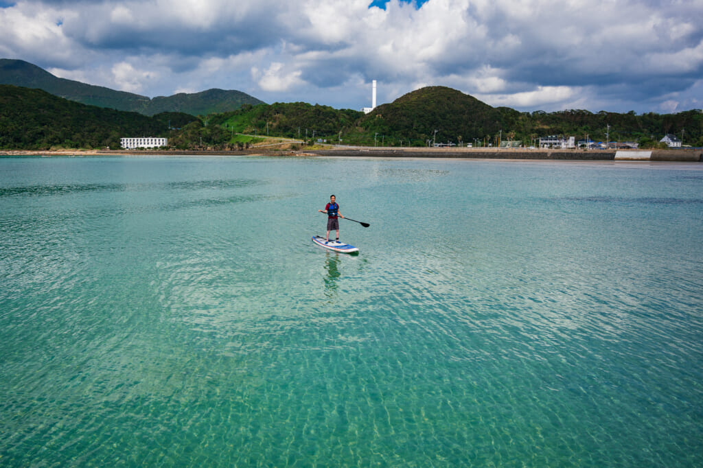un homme faisant du stand up paddle sur des eaux calmes