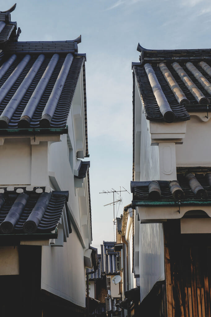 Deux maisons japonaises traditionnelles aux toits de tuiles séparées par une ruelle étroite