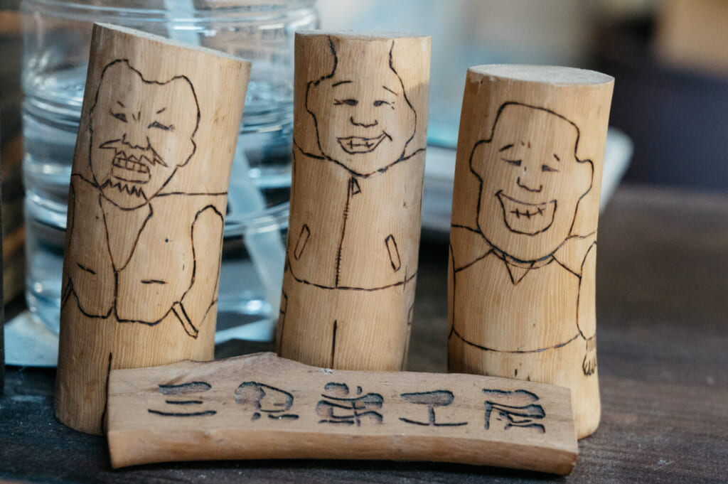 Illustrations pyrogravées sur du bois de camélia, représentant les trois fondateurs de Sankyodai Kobo