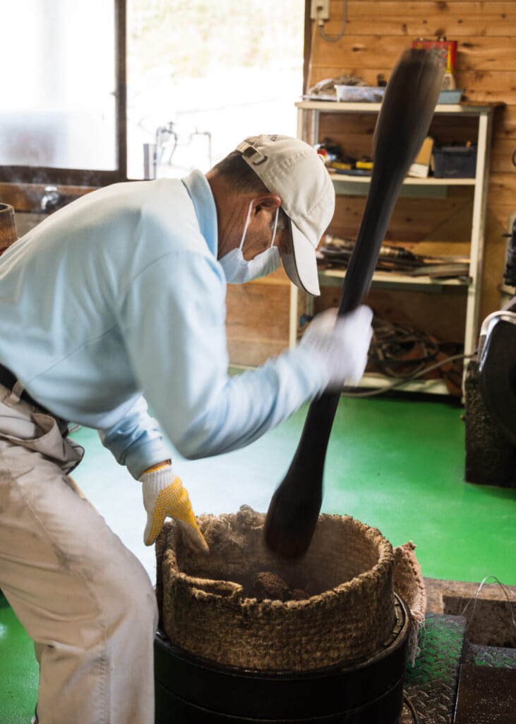 Producteur de tsubaki pilant les graines à l'ancienne