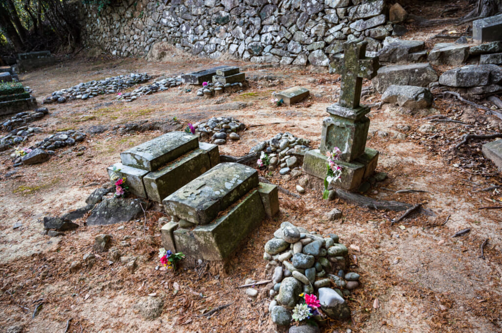 Tombes dans le cimetière chrétien de Hisaka à Goto : tas de pierres pour les chrétiens cachés et croix traditionnelles plus récentes