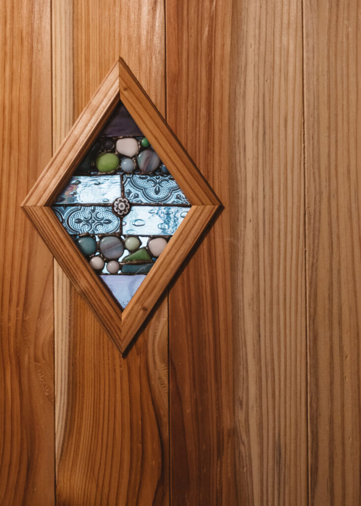 Petit vitrail en forme de losange incrusté dans une porte en bois