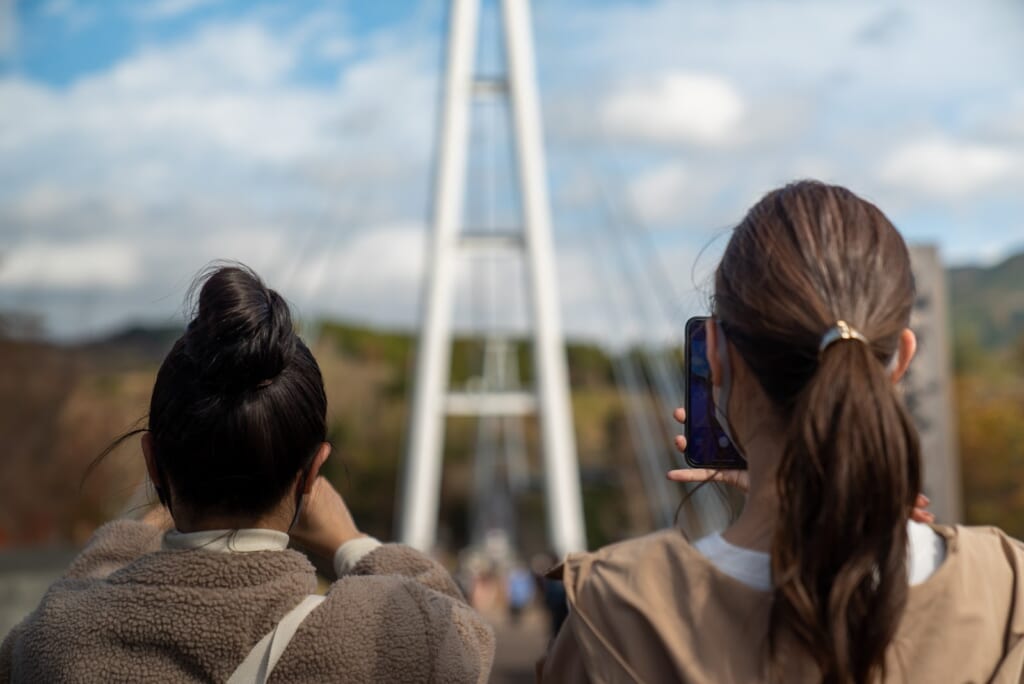 visiteur photographiant le pont suspendu de kokonoe