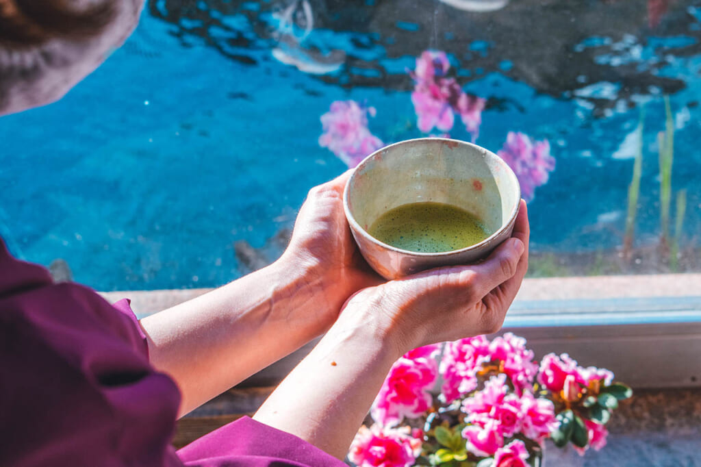 Mais tenant un bol de thé matcha