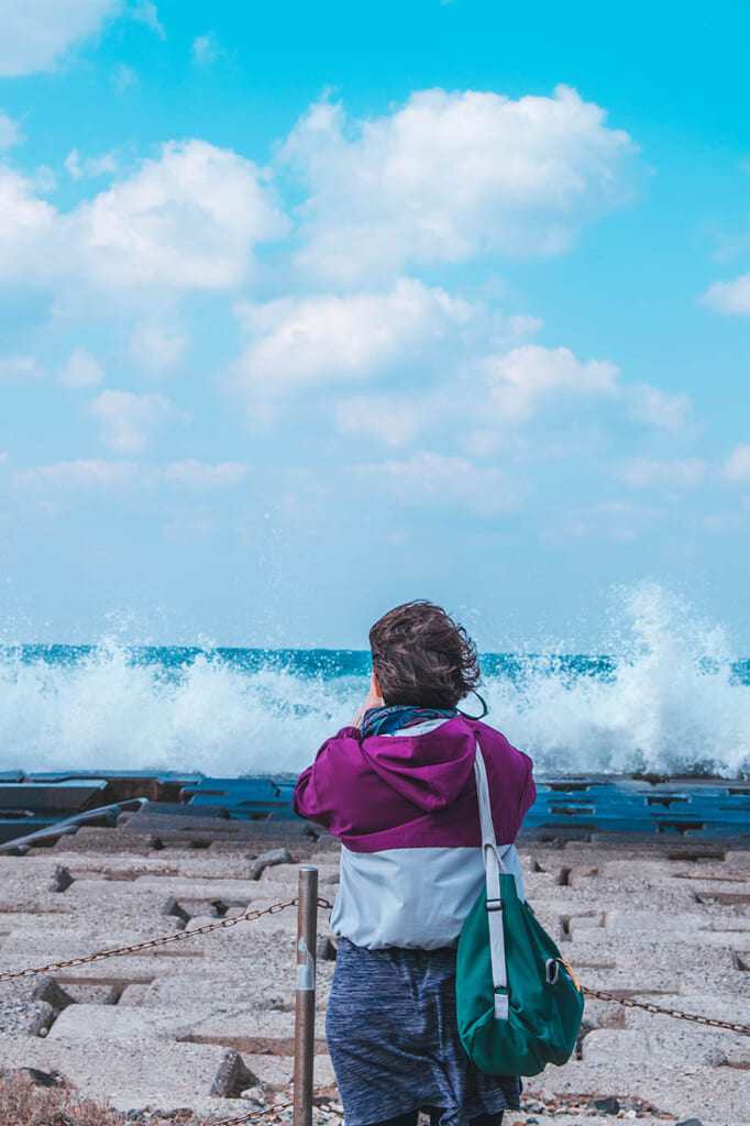 personne se tenant face à la mer sur une digue