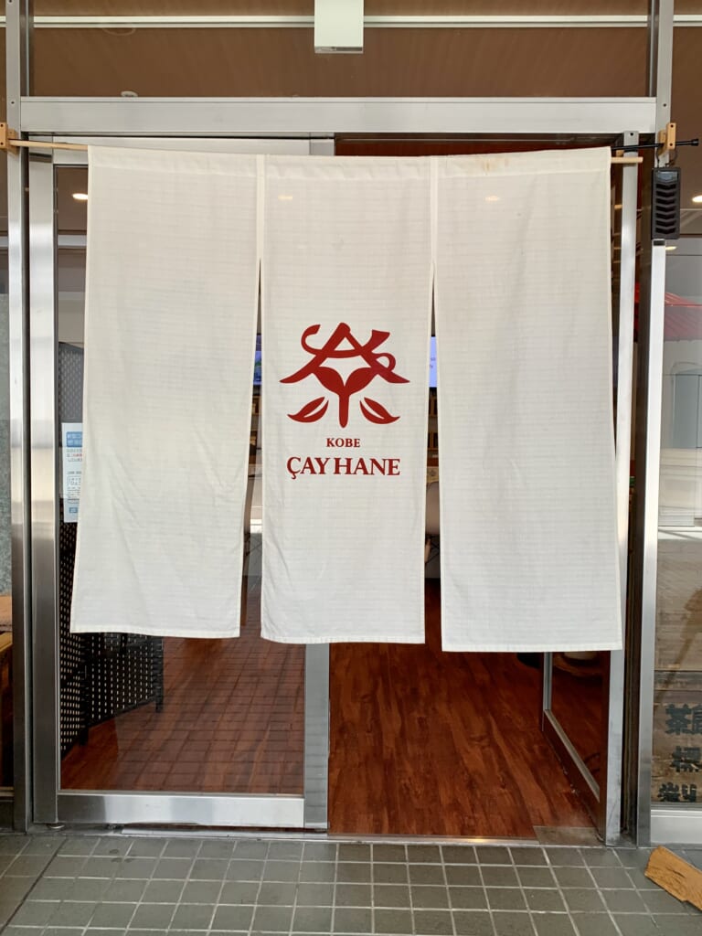 Noren d'un magasin de thé qui sert des soba au matcha. Notez le détail du kanji qui signifie "thé" et qui est dessiné avec des feuilles de thé.