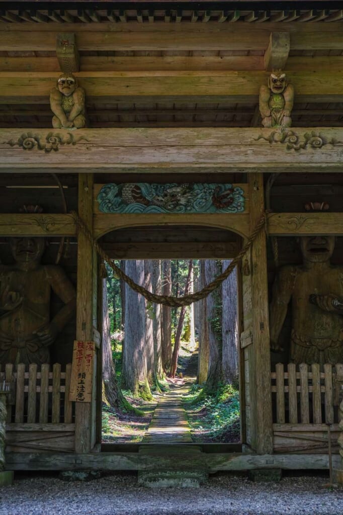 Porte Niomon ouvrant sur une allée bordée de cèdres, dans un santuaire japonais