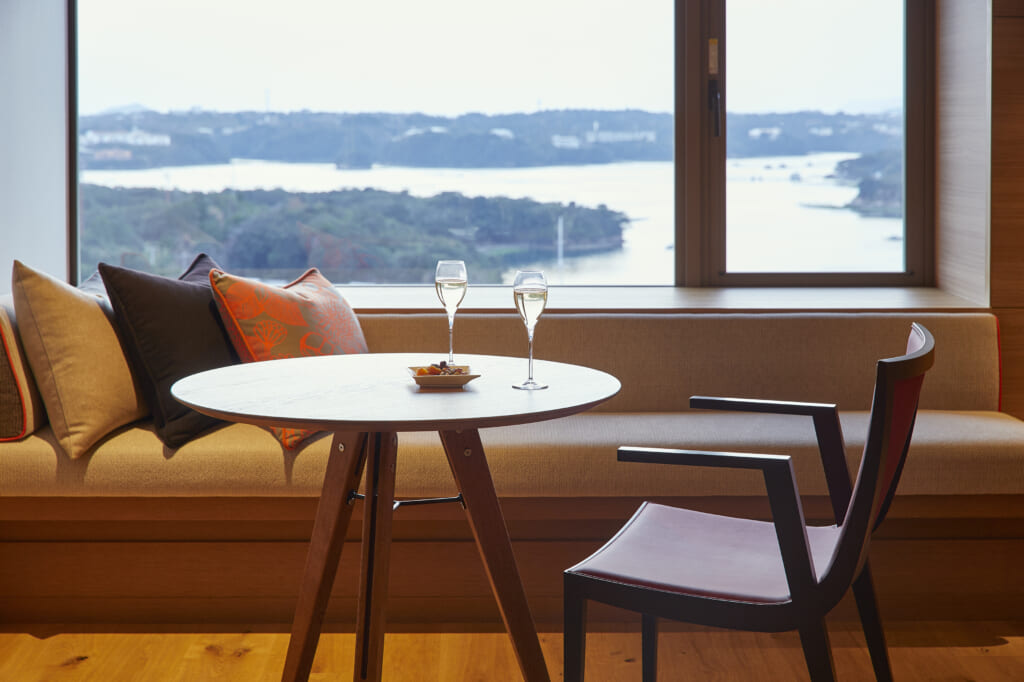 une ve sur la bais d'Ago dans la prefecture de Mie au Japon depuis une chambre d'hotel. Une table est placée devant la fenêtre sur laquelle se trouve deux coupes de champagnee