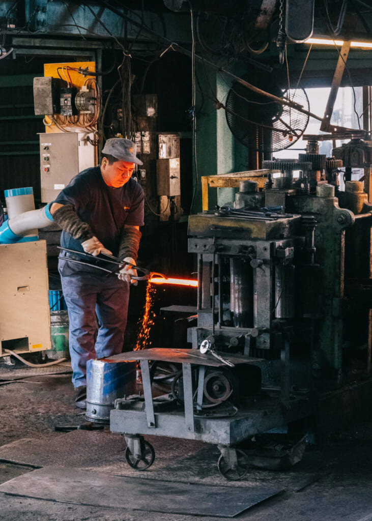 un artisan de yamamura maniant du métal brulant