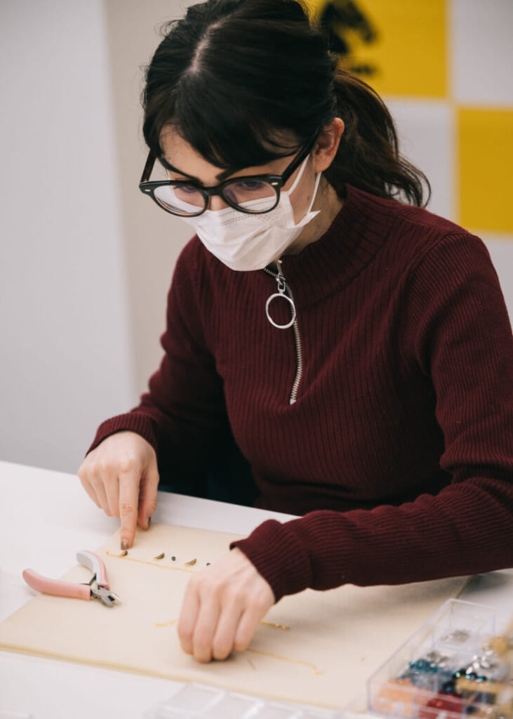 une femme assemble un bijoux lors d'une initiation dans une usine au Japon