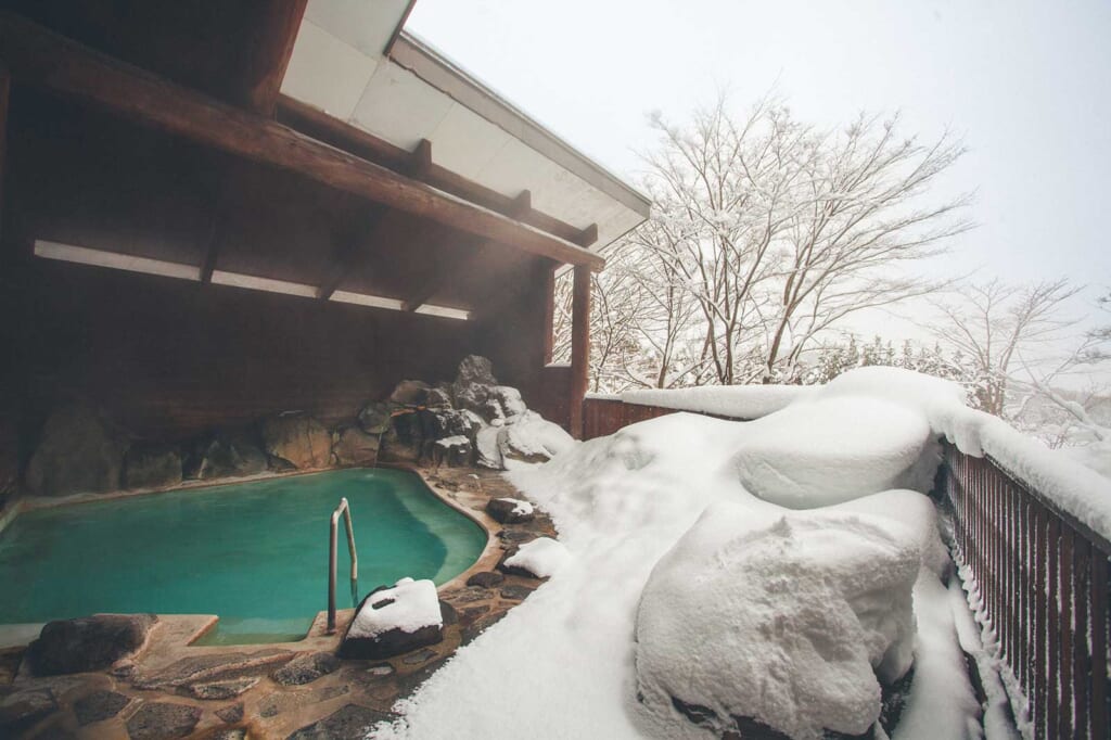 Bain extérieur d'un onsen japonais entouré de neige à Semboku