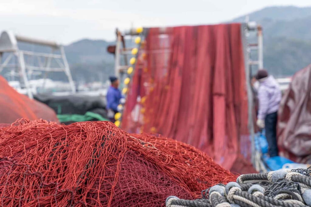 Filet de pêche rouge derrière lequel travaillent des pêcheurs