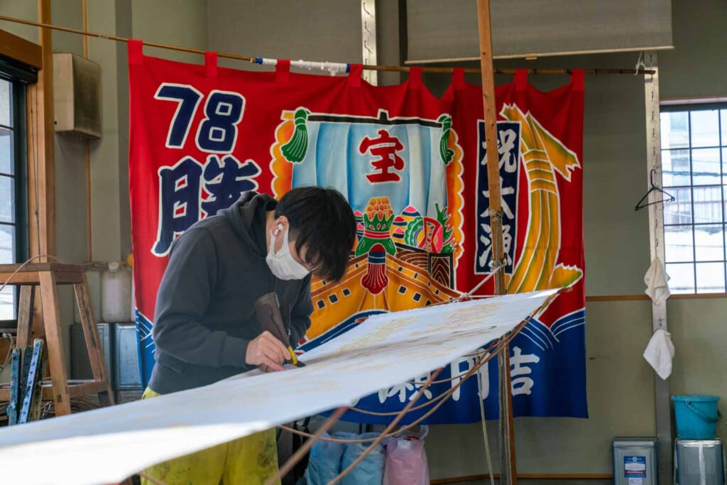 Un artisan japonais entrain de dessiner sur un drapeau vierge
