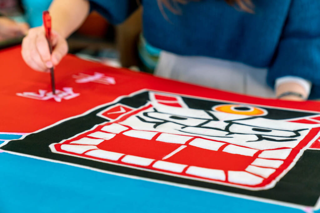 Un artisan peint un drapeau japonais selon des techniques traditionnelles