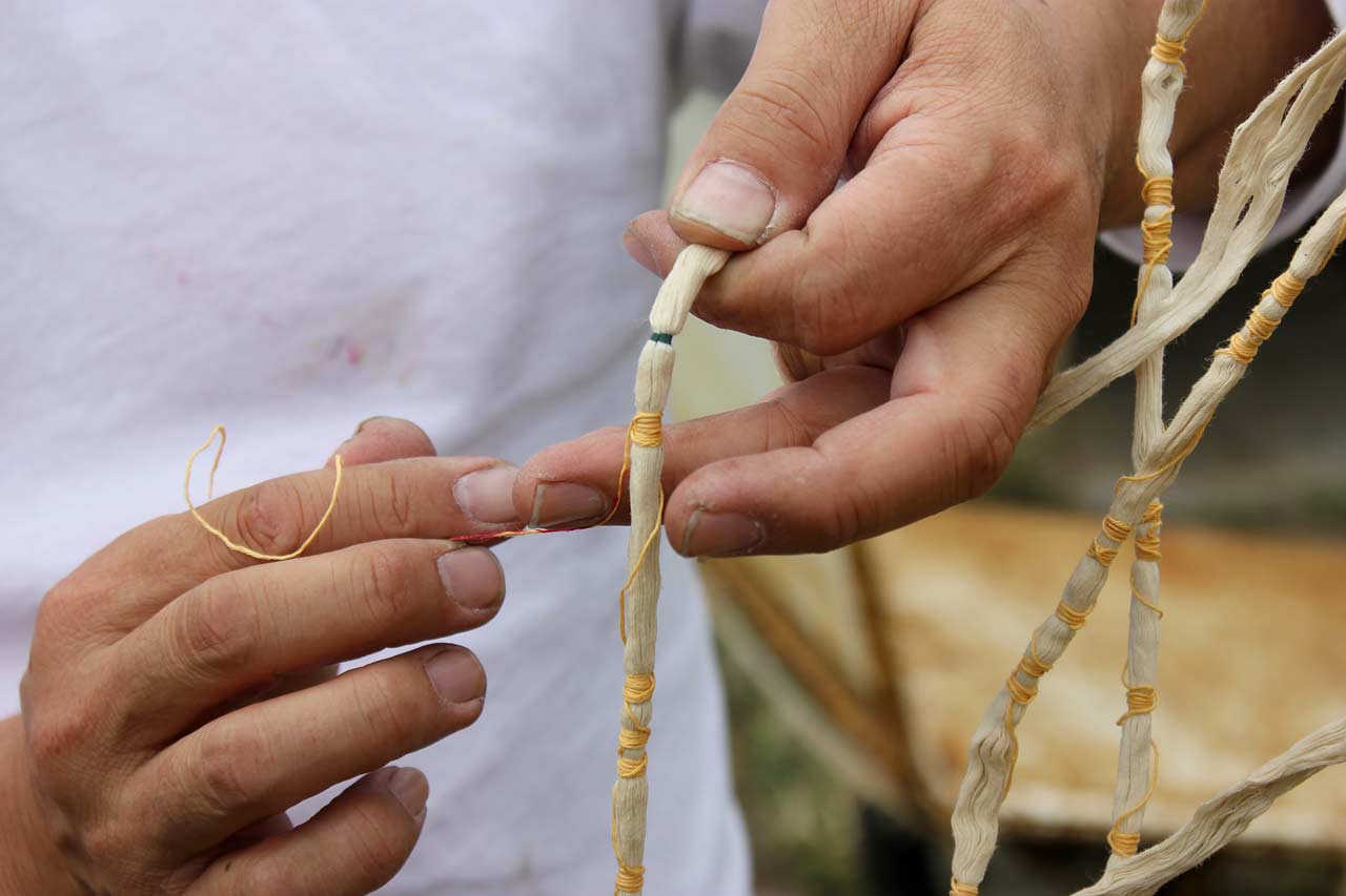 Un homme noue des fils autour des parties indiquées sur l'échevette.