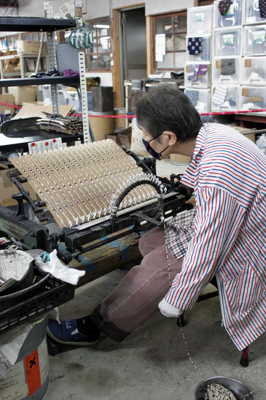 Une femme file une échevette sur des navettes à l'atelier Sakata Orimono de Hirokawa.