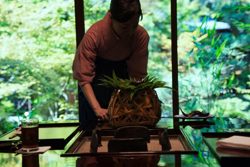 Une femme servant du poisson Ayu grillé dans un restaurant japonais à Tokyo