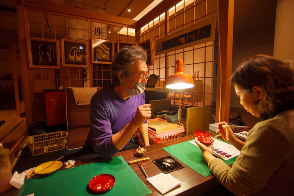 Un artisan japonais explique à une cliente comment déposer de la laque