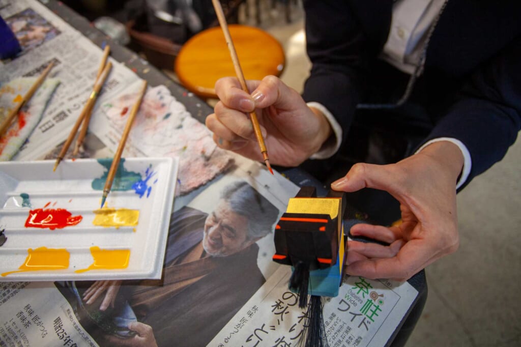 Une artisane en train de peindre une poupée en papier mâché