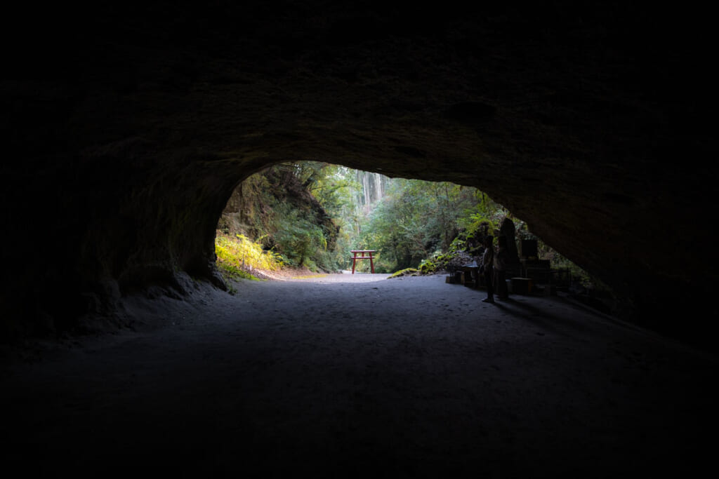 Une immense grotte japonaise au bout de laquelle se tient une porte torii