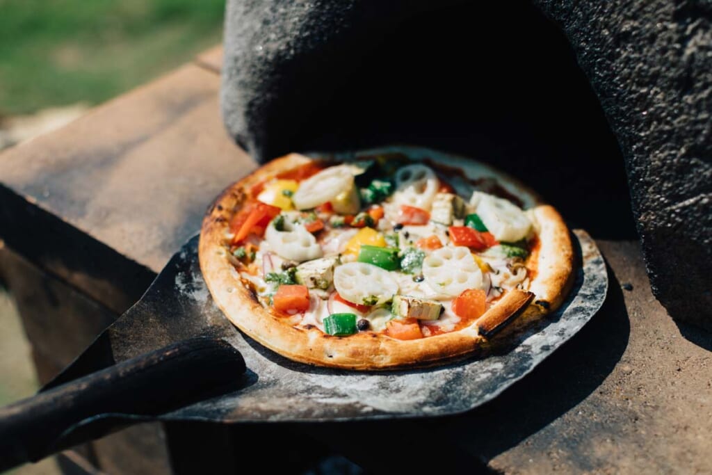 Pizza sortie d'un four à bois composée de racine de lotus renkon et d'autres ingrédients japonais