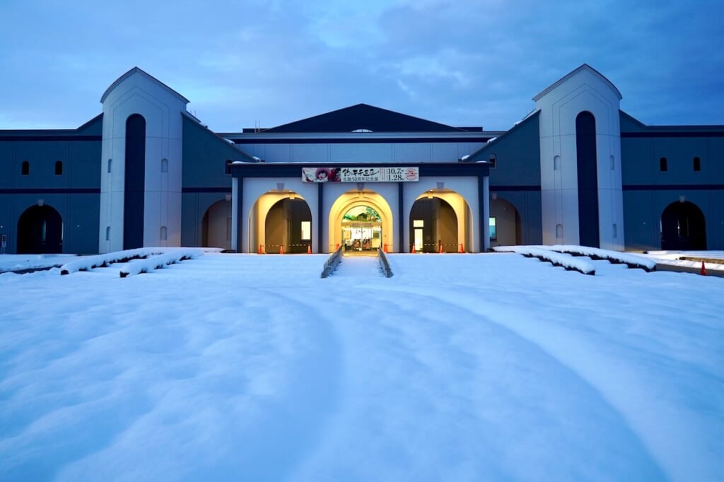 extérieur du Musée du Manga de Yokote Masuda au bout d'une place couverte de neige en fin de journée