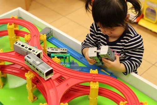 Niña jugando con trenes de juguete en Japón