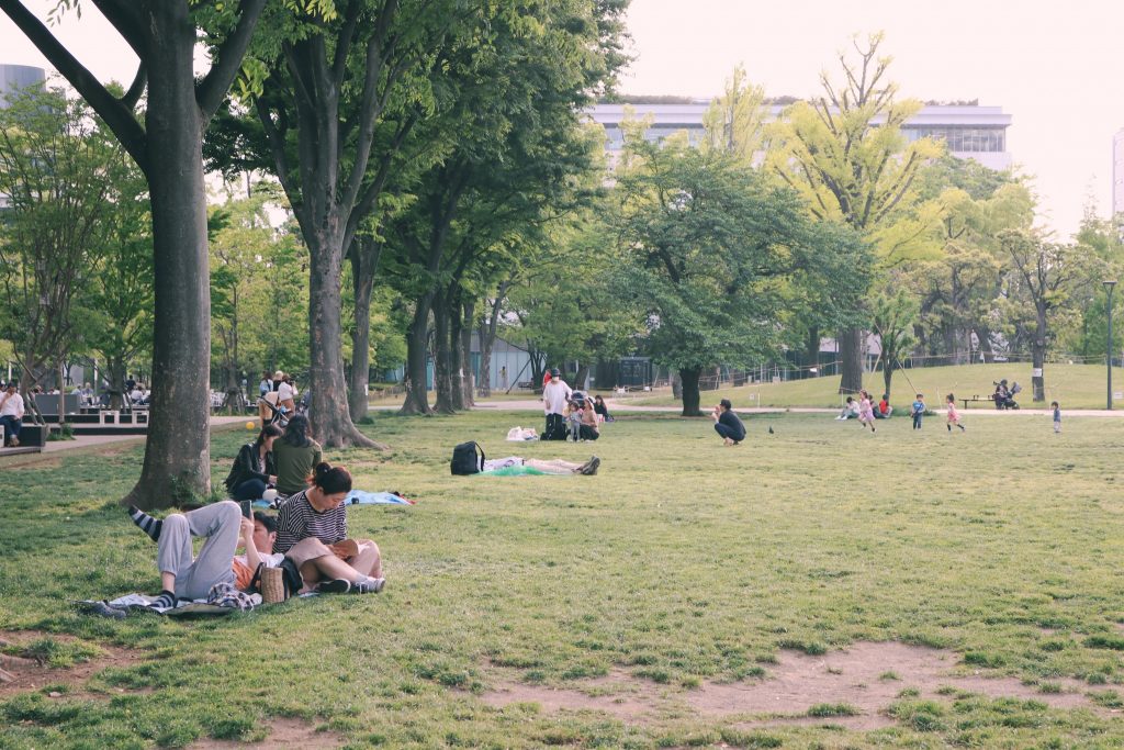 Gente disfrutando del buen tiempo sentados en la hierba en Shiki no Mori