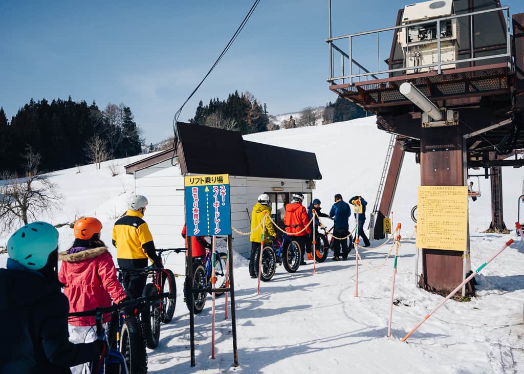 Fila de personas subiendo el telesillas para hacer snow cycling