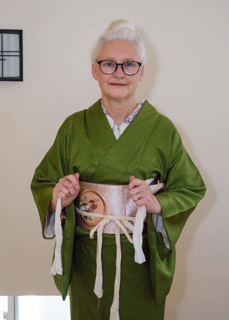 Agarrando las tiras del obi-makura por delante