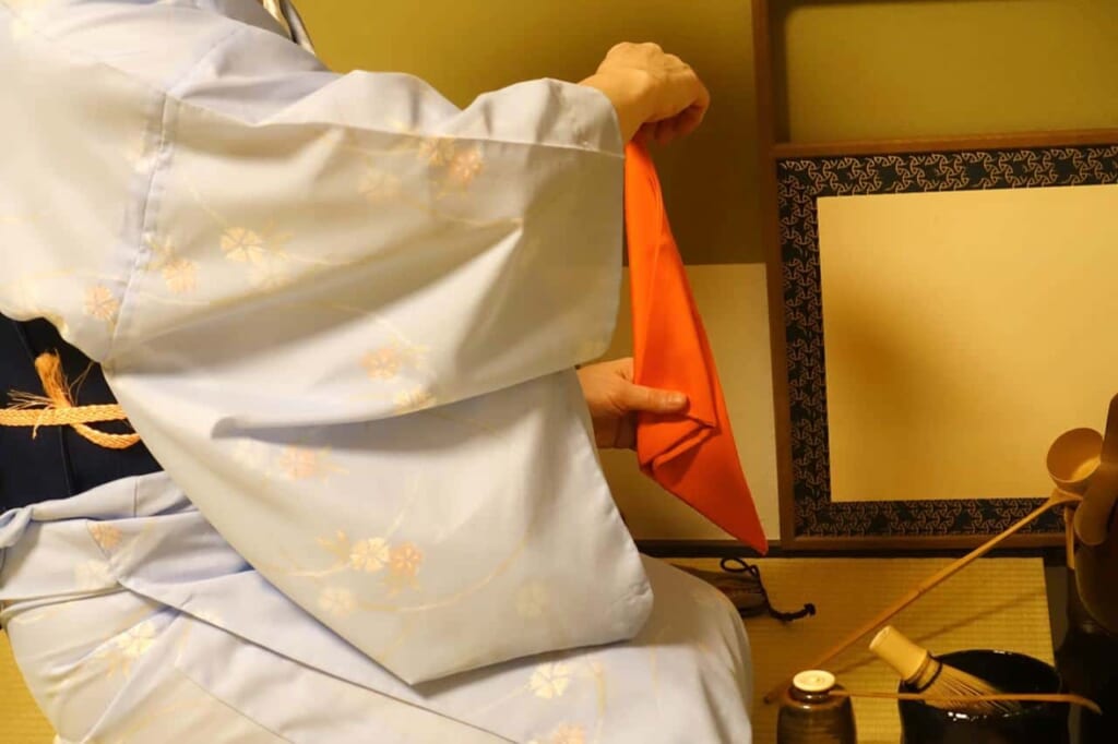 Mika pliega y despliega varias veces el fukusa durante el taller de la ceremonia del té en Tokio