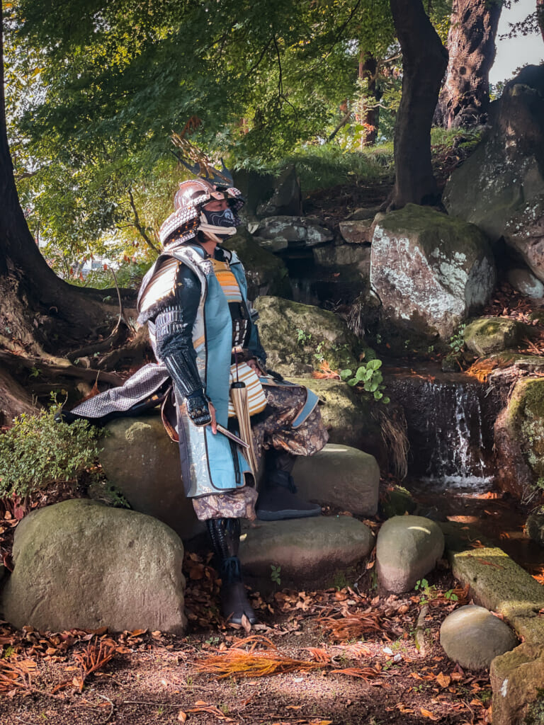 persona vestida de samurai al lado de una cascada