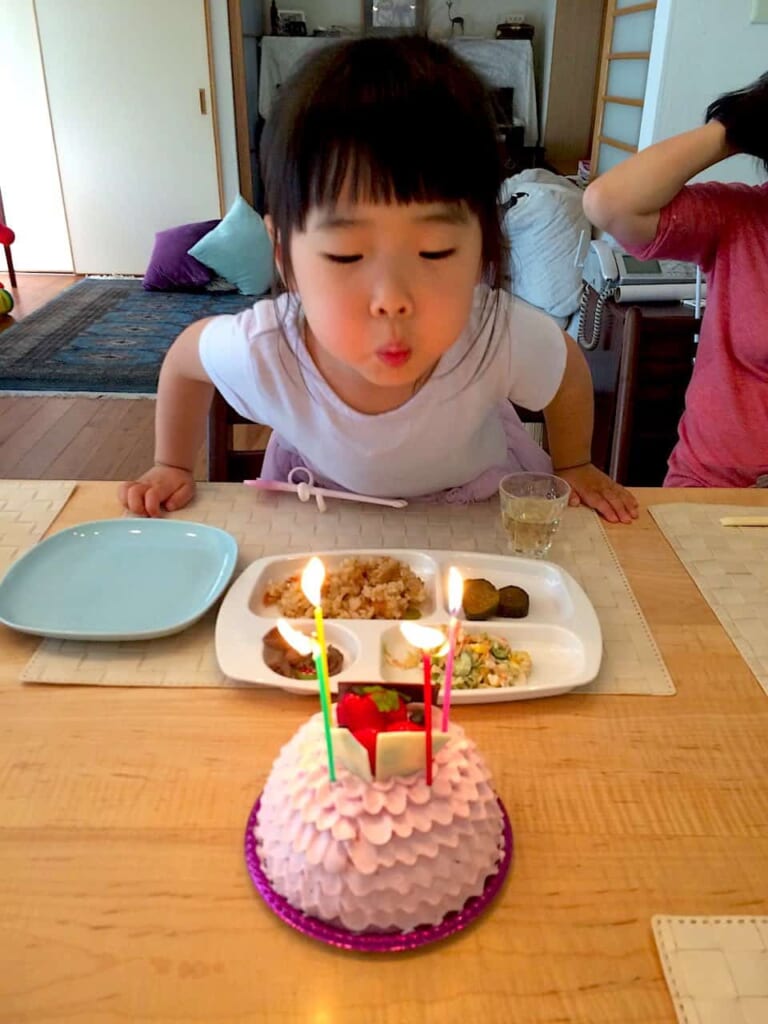 niña japonesa soplando velas