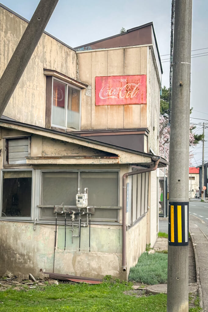 Una casa abandonada en Morioka con un cartel de coca-cola