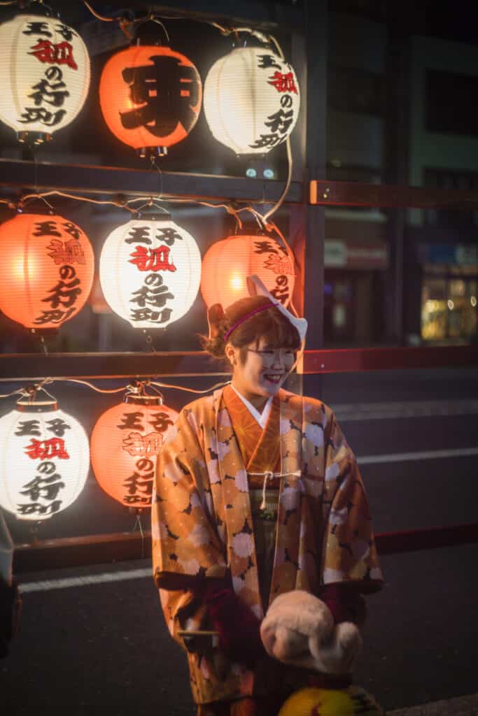 Mädchen im Kimono und Fuchsmaske auf dem Kitsune no Gyoretsu Fest in Oji.