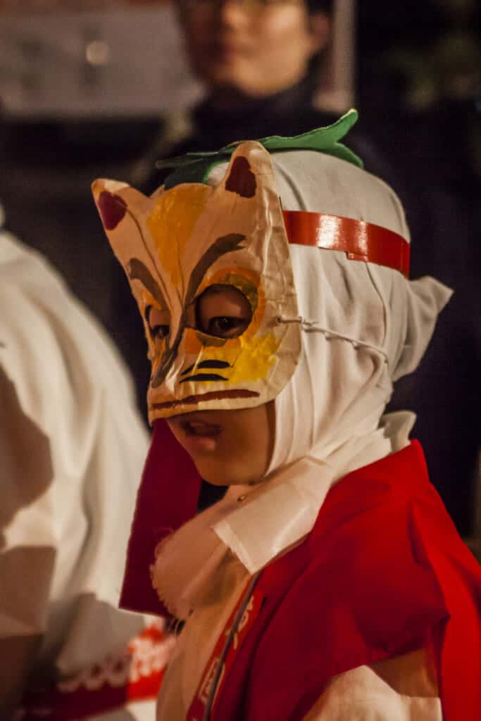 Ein Kind mit einer Fuchsmaske auf dem Kitsune no Gyoretsu Fest.