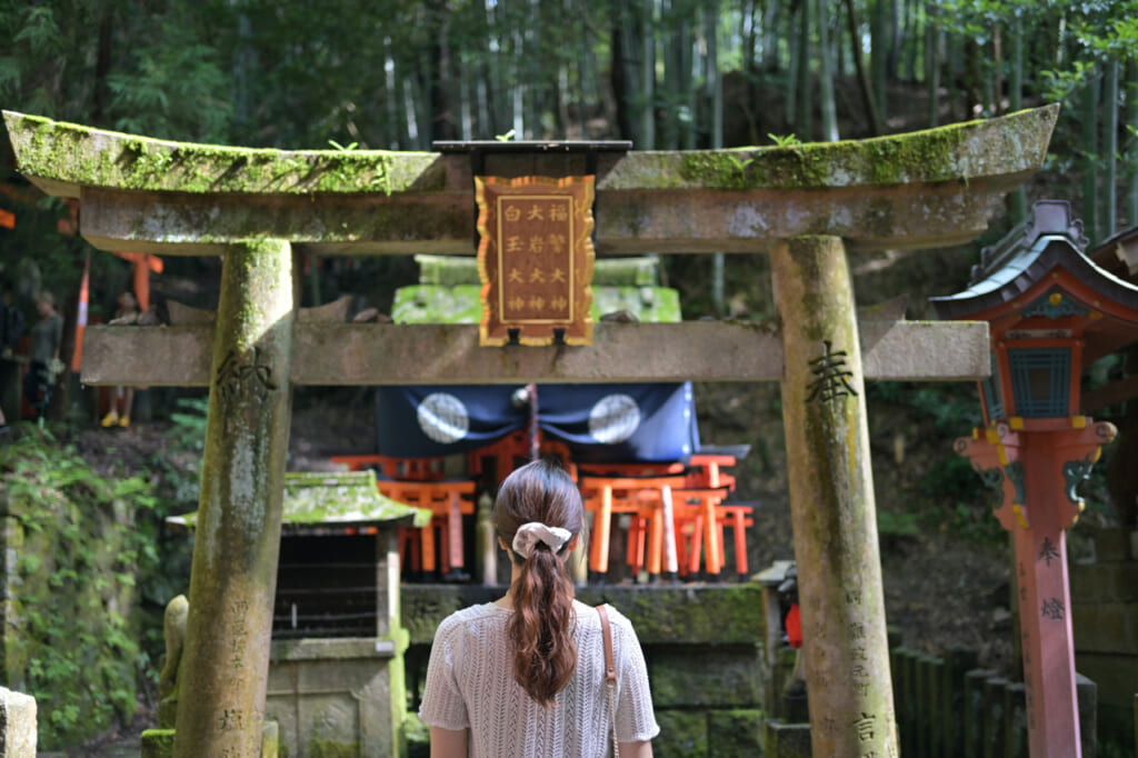 Frau vor einem steinernen Torii-Tor